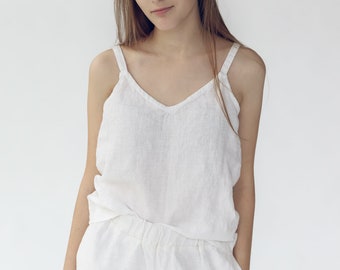 Peut inclure: Une femme portant un débardeur en lin blanc et un pantalon assorti. La tenue est simple et décontractée, parfaite pour une journée chaude.
