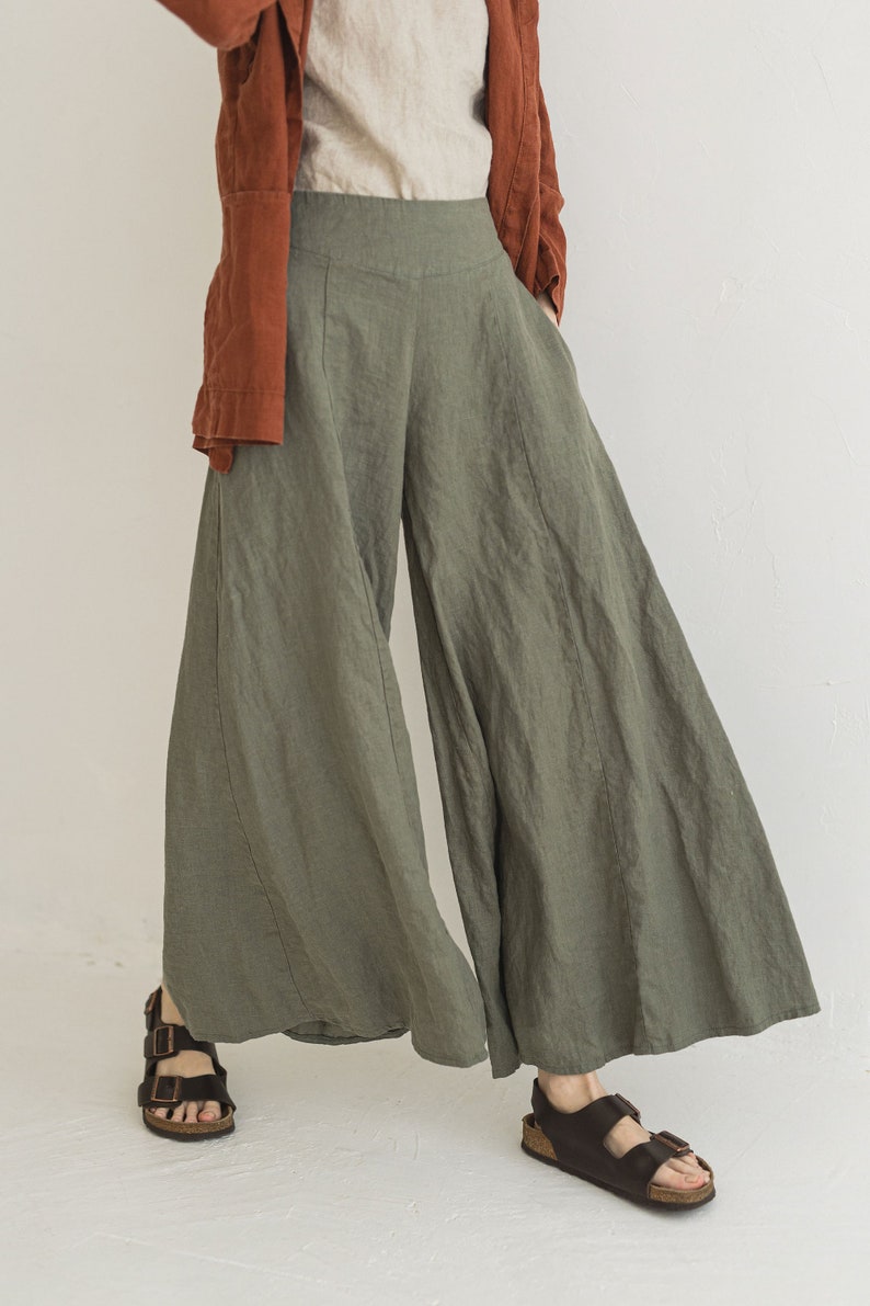 May include: A pair of wide-leg, green linen pants with a high waist and a relaxed fit. The pants are made of a lightweight, breathable fabric and have a flowy silhouette.