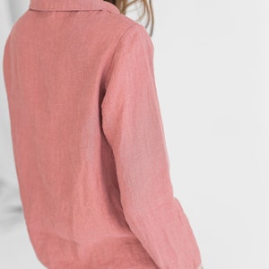 May include: A long-sleeved, collared shirt in a dusty rose colour. The shirt is made of a soft, textured fabric and has a relaxed fit.