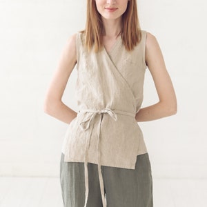 May include: A woman wearing a beige linen wrap top with a tie at the waist and matching green linen pants.