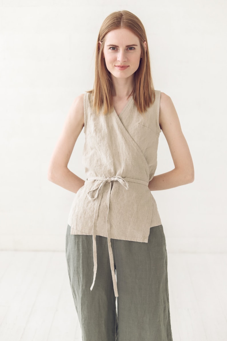 May include: A woman wearing a beige linen wrap top with a tie at the waist and matching green linen pants.