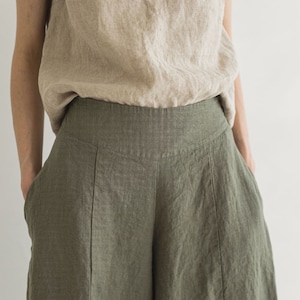 May include: A pair of wide-leg linen pants in a dark green color. The pants have a high waist and are made of a lightweight, breathable fabric.