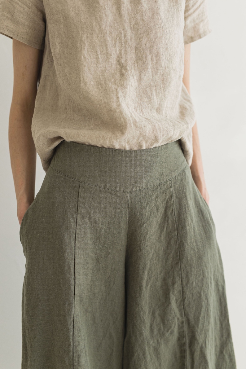 May include: A pair of wide-leg linen pants in a dark green color. The pants have a high waist and are made of a lightweight, breathable fabric.