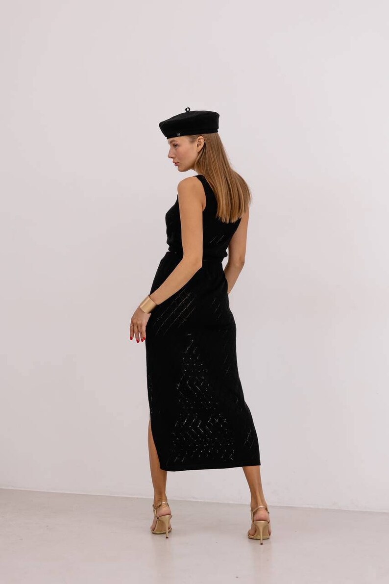 May include: A black sleeveless midi dress with a geometric pattern and a side slit. The dress is paired with a black beret and gold heeled sandals.