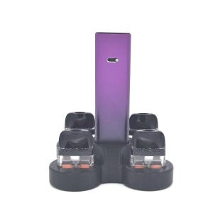 Puede incluir: Un soporte de carga negro con cinco ranuras para cápsulas de vape. El soporte tiene un dispositivo de vape morado en el centro.
