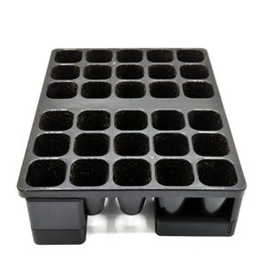 May include: A black plastic seed tray with 32 individual square cells. The tray is designed for starting seeds, with a raised base for drainage. The cells are filled with a dark, soil-like material.
