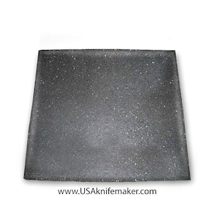 May include: A black square-shaped chopping board with a speckled surface. The board is made of a durable material and is ideal for cutting and preparing food.