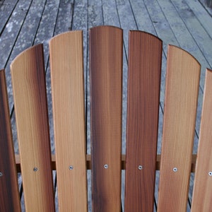 May include: Close-up of a wooden chair back with seven slats. The slats are a mix of light and dark brown wood, creating a natural wood grain pattern.