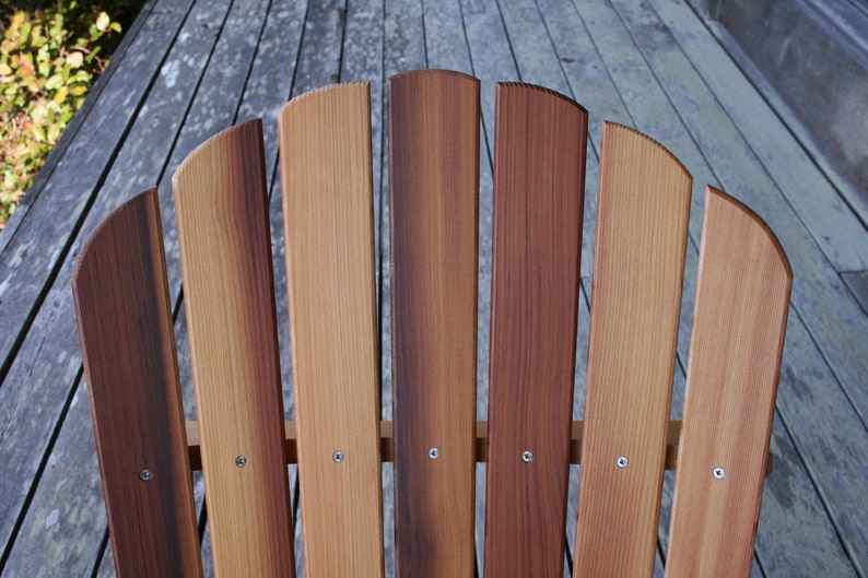 May include: Close-up of a wooden chair back with seven slats. The slats are a mix of light and dark brown wood, creating a natural wood grain pattern.