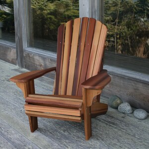 May include: A wooden adirondack chair with a natural wood finish. The chair is made of cedar wood and has a slatted back and seat. The chair is sitting on a wooden deck.