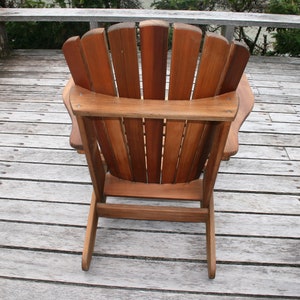 May include: A wooden adirondack chair with a natural wood finish. The chair is on a wooden deck.