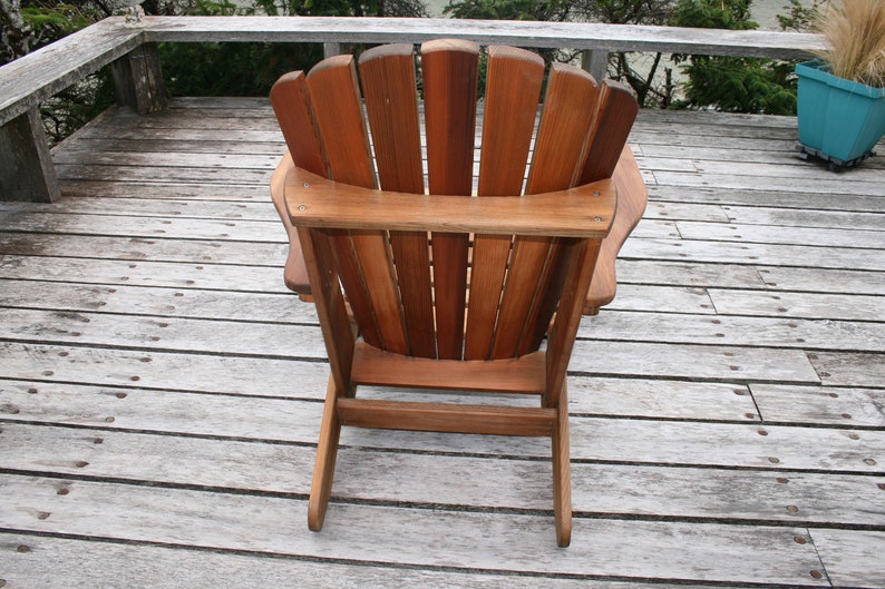 May include: A wooden adirondack chair with a natural wood finish. The chair is on a wooden deck.