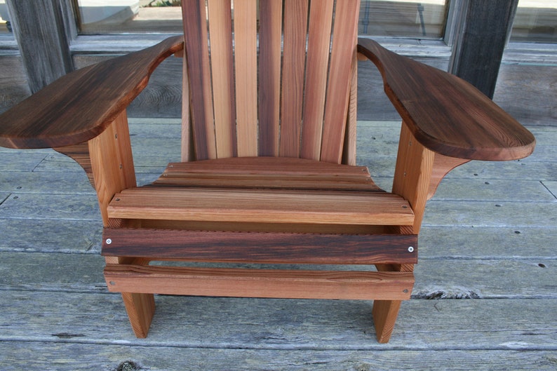 May include: A wooden adirondack chair with a natural wood finish. The chair has a wide, comfortable seat and armrests. The chair is made of solid wood and is designed for outdoor use.