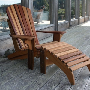 May include: A wooden adirondack chair with a matching footrest. The chair and footrest are made of natural wood with a reddish-brown color.