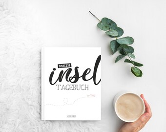 May include: White journal with black text that reads "Mein Insel Tagebuch" and a small paper boat illustration. The journal is on a white fluffy surface.