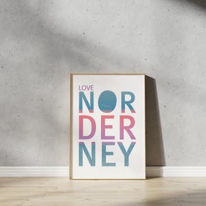 May include: A framed print with the text "LOVE NORDERNEY" in a blue, pink, and white gradient. The text is in a bold, sans-serif font.