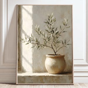 Puede incluir: Una impresión de arte mural vertical que presenta una pintura al óleo de un pequeño olivo en una maceta de cerámica beige redondeada. La planta está colocada sobre una repisa contra una pared de tonos neutros con luz lateral suave.
