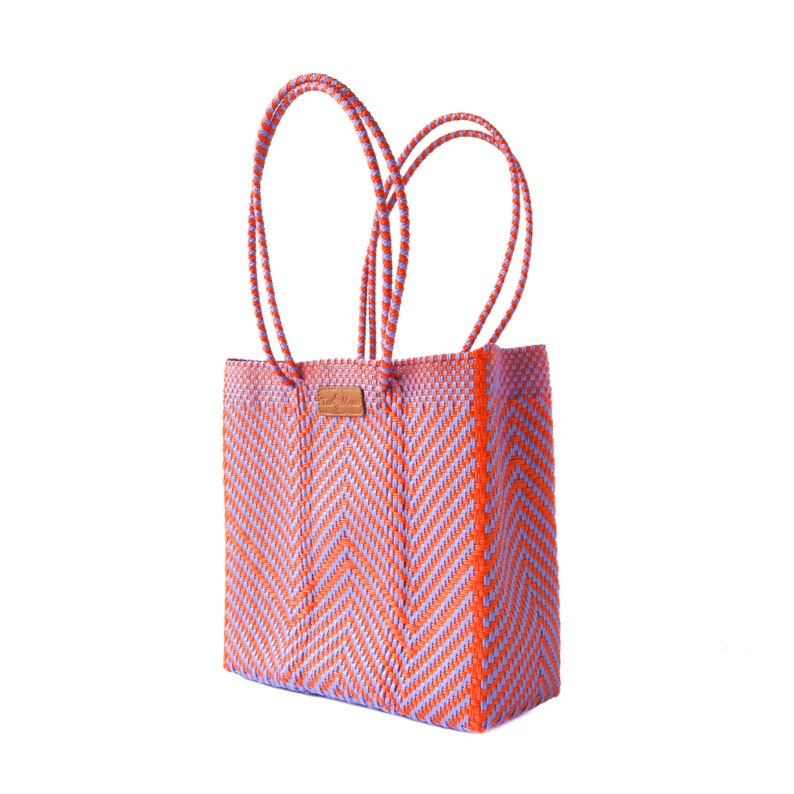 May include: A large, orange and purple woven tote bag with double handles. The bag has a chevron pattern.
