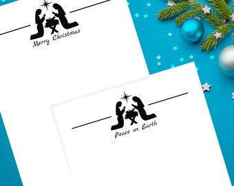 Puede incluir: Dos tarjetas navideñas blancas con siluetas negras del Nacimiento. Una tarjeta dice "Merry Christmas", la otra "Peace on Earth". Las tarjetas están sobre un fondo azul con decoraciones navideñas.
