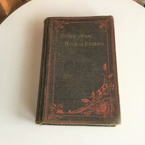 Könnte beinhalten: Ein antikes Hardcover-Buch mit einem dunkelgrünen Einband und roten Lettern. Der Titel des Buches lautet "Notes on the Book of Exodus".