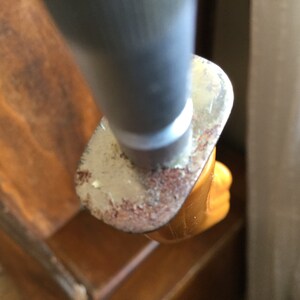 Op de afbeelding: Close-up van een meshandvat. De handgreep is felgeel, met een zilverkleurige metalen lemmetbeschermer. De lemmetbeschermer heeft een versleten, getextureerde uitstraling met roestkleurige verkleuringen.