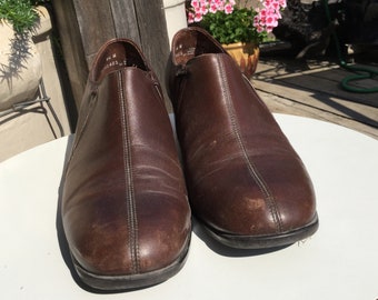 May include: A pair of brown leather ankle boots with a zipper on the side. The boots have a slightly pointed toe and a low heel.