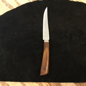 May include: A silver butter knife with a brown plastic handle.
