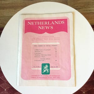 May include: A vintage Netherlands News publication dated 15 April 1945, featuring a pink cover with white text. The front displays the title, regional information, a table of contents, a green emblem with a lion, and publication details.