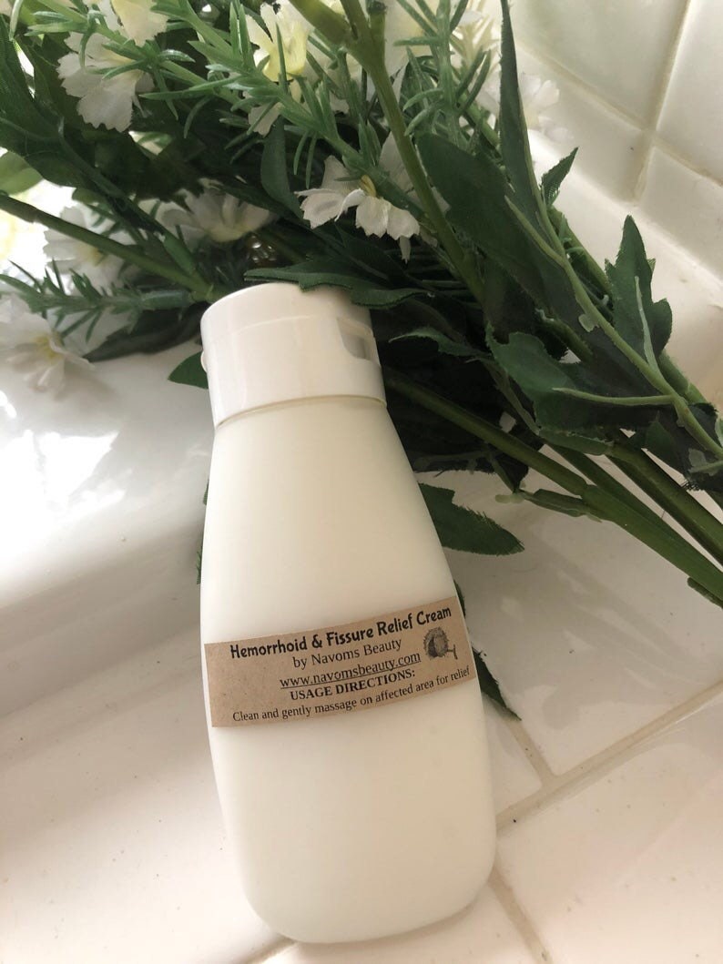 K&ouml;nnte beinhalten: Wei&szlig;e Plastikflasche mit H&auml;morrhoiden- und Analfissuren-Salbe mit einem braunen Etikett, auf dem steht: "Hemorrhoid & Fissure Relief Cream by Navoms Beauty www.navomsbeauty.com USAGE DIRECTIONS: Clean and gently massage on affected area for relief"