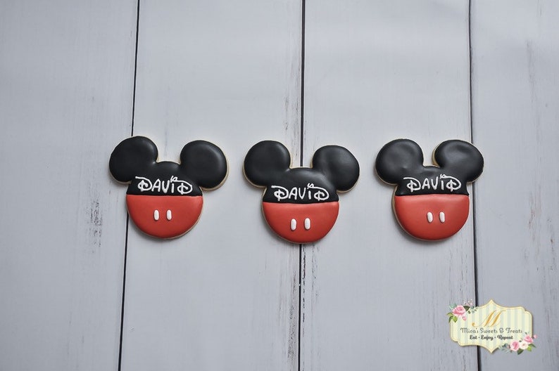 May include: Three red and black Mickey Mouse-shaped cookies with white icing and the name "DAVID" written on each cookie.