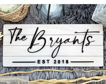 May include: White wooden sign with the text "The Bryants EST 2018" in black lettering. The sign has a rustic, farmhouse style.