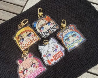 Puede incluir: Una colección de llaveros de acrílico transparente con diseños de personajes de estilo anime. Cada llavero tiene un cierre dorado y representa un personaje diferente con peinados y expresiones únicas. Algunos llaveros tienen texto como "Cookie" y "Made in Canada".