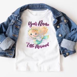 May include: White t-shirt with a mermaid illustration and the text "Your Name the Little Mermaid" in purple.