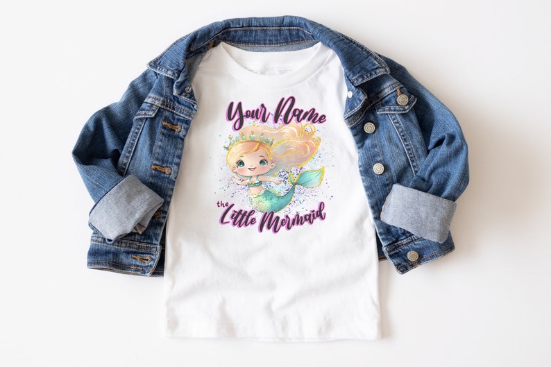 May include: White t-shirt with a mermaid illustration and the text "Your Name the Little Mermaid" in purple.