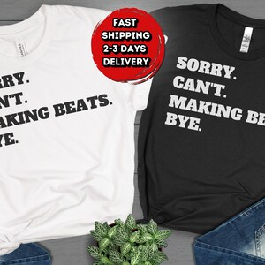 May include: Two t-shirts with the text "Sorry. Can't. Making Beats. Bye." on them. One shirt is white with black text, and the other is black with white text.