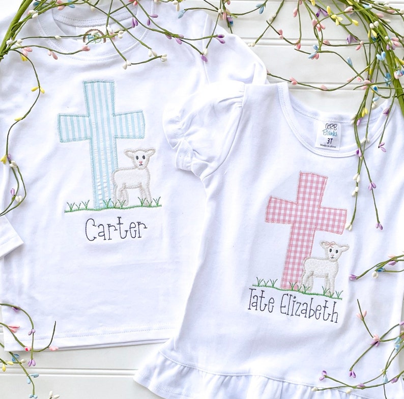 May include: Two white t-shirts with embroidered crosses and lambs. The cross on the left shirt is blue and white gingham, and the cross on the right shirt is pink and white gingham. The shirts are personalized with the names "Carter" and "Tate Elizabeth".