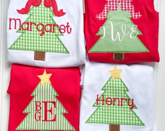 May include: Four Christmas-themed shirts. Two white shirts with green gingham Christmas trees, one with a red bow and the name "Margaret", the other with the name "Henry". Two red shirts with green and white striped Christmas trees, one with a yellow star and the initials "BGE", the other with a red and white checkered bow and the initials "WE".