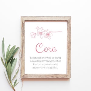 May include: A printable art print featuring a pink floral illustration and the name "Cora" in pink script. The print includes the meaning of the name: "she who is pure; a maiden; lovely; graceful; kind; compassionate; inquisitive; delightful."
