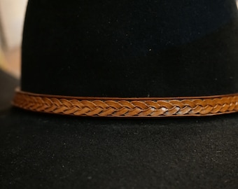 May include: A black felt hat with a brown leather braided band around the crown.