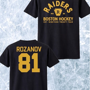 May include: Black t-shirt with gold lettering and graphics. The front displays "RAIDERS BOSTON HOCKEY" and "EST. NINETEEN TWENTY FOUR." The back features "ROZANOV" and the number "81."