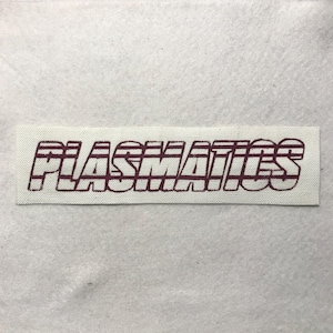 May include: A rectangular off-white fabric patch featuring the word PLASMATICS embroidered in a dark maroon thread. The lettering has a bold, blocky, and slightly slanted style with horizontal line details running through each letter.