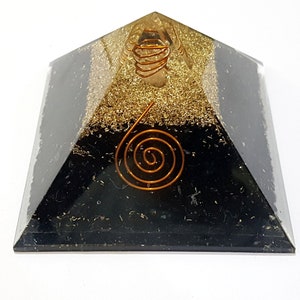 May include: Black obsidian pyramid with a copper wire spiral inside. The pyramid is layered with gold flakes and clear quartz.