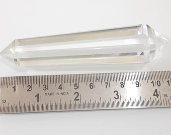 May include: A clear, double-terminated quartz crystal wand, approximately 4 inches long, lies next to a metal ruler. The crystal has a rectangular body with pointed ends. The ruler is marked in inches and features the text "MADE IN INDIA."