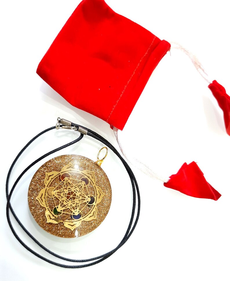 May include: A gold-colored pendant with a geometric design and colorful stones, on a black cord, with a red velvet pouch.