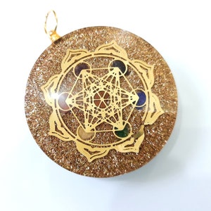 May include: Gold-toned pendant with a clear resin background and a gold geometric design with seven colorful gemstones. The pendant is surrounded by a gold flower design.