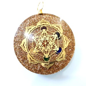 May include: Gold pendant with a clear resin background and a gold-toned geometric design with colorful stones. The pendant features a flower-shaped design with a star inside.