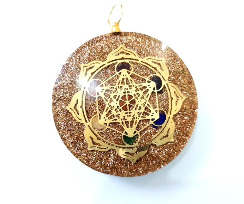 May include: Gold pendant with a clear resin background and a gold-toned geometric design with colorful stones. The pendant features a flower-shaped design with a star inside.