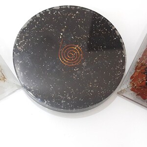 Könnte beinhalten: Drei Kristall-Orgonit-Pyramiden mit Kupferspiralen. Die Pyramiden bestehen aus klarem Quarz, schwarzem Obsidian und rotem Jaspis.