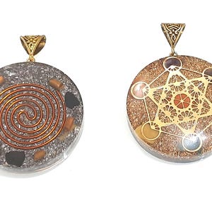May include: Two round pendants with gold metal bail loops. The pendant on the left has a silver background with a copper wire spiral design and black and brown stones. The pendant on the right has a brown background with a gold metal geometric design and multi-coloured stones.