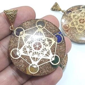 Pu&ograve; includere: Ciondolo in oro con un design in resina trasparente che presenta un motivo geometrico e sette pietre colorate. Il ciondolo &egrave; su una catena d'oro.